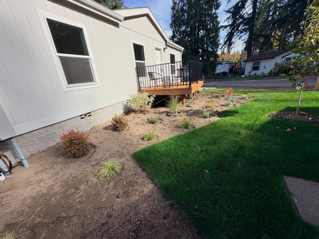 New planting beds and fresh green lawn beside a mobile home with a new deck